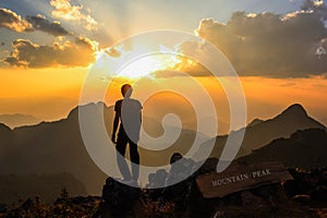 Man standing on mountain peak at sunset