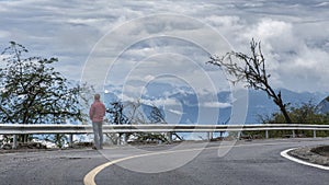 A man standing by the mountain road