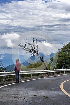 A man standing by the mountain road