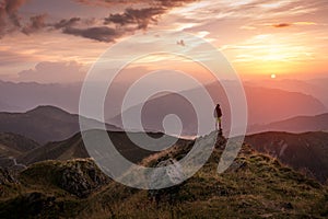 Man standing on a mountain summit at sunset