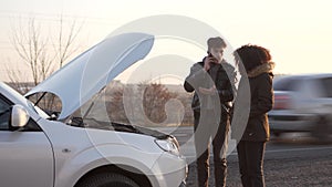 Man standing near broken car and calling for help on phone