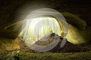 Man standing near huge cave entrance