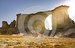 A man is standing near a mountain range with the blue sky and sunlight in the background