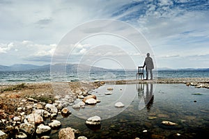 Man standing next to a chair outdoors