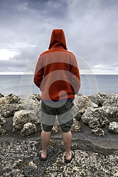 Man standing next to the ocean looking over a seawall