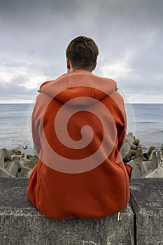 Man standing next to the ocean looking over a seawall