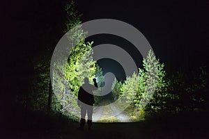Man standing outdoor at dark night shining with flashlight photo