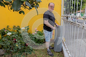 Man standing in the outdoor garden before the placement of a metal mesh on the fence of a house