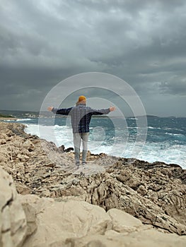 Man standing outdoors close the sea with arms out on windy day