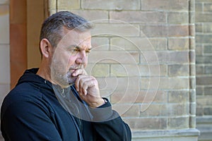 Man standing outside a brick building deep in thought