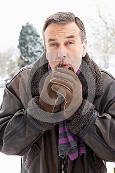 Man Standing Outside In Snow Warming Hands