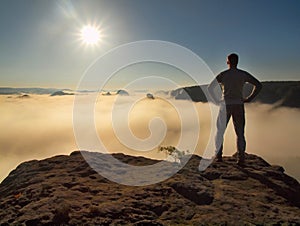 Man is standing on the peak of sandstone rock in national park Saxony Switzerland and watching over the morning misty valley