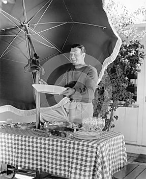 Man standing at a picnic table and holding a plate