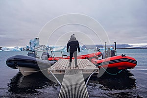 The man standing on pier in winter. Stylish winter clothes. Icebergs in Jokulsarlon lagoon