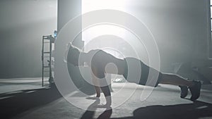 Man standing in plank. Guy doing push ups during fitness session in sport club