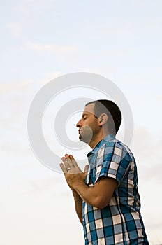 Man standing and praying on a hillside.