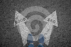 Man standing on road with direction arrow choices Good and Bad