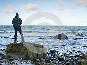 Man standing on rock in the middle of ocean. Tourist stand alone