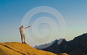 Man Standing on Rock Summit in Desert