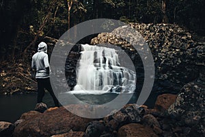 Man standing on rocks with waterfall
