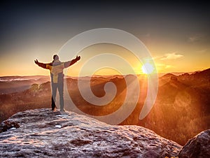 Man standing at rocky edge. Young man watching sunrise at hilly horizon.