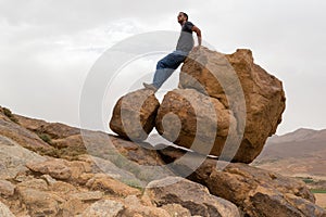 Man standing on round big rocks on the edge of a mountain