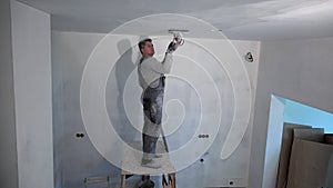 Man standing on scaffolding polishing ceiling with grinder machine