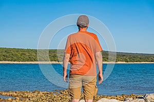 Man standing on shore and observing the sea surface, Losinj island, Croatia