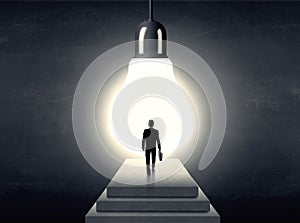 Man standing on a step in front of a huge light bulb