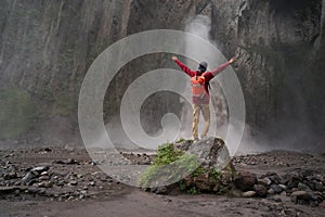 Man standing on stone and looking on waterfall