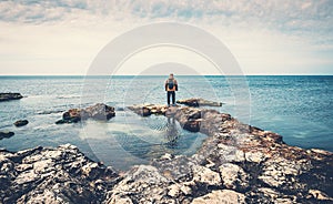 Man standing on stones at sea coast looking at horizon. Beach, ocean travel and freedom concept