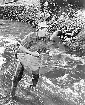 Man standing in a stream of water fishing