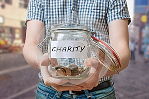 Man standing on street is collecting money for charity and holds jar