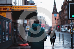 Man standing in the street in a raincoat - shot from back