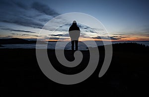 Man standing in sunset above valley