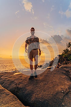 Man standing on the sunset on the cliff near ocean