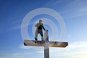 Man Standing on Tall Cross