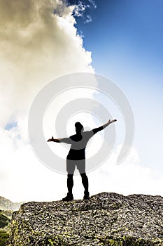 Man standing on top of a cliff with arms raised