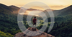 Man standing on top of cliff at sunset