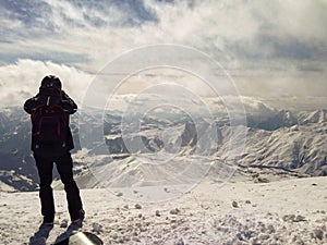 Man standing on top of mountains with great view of snowy landscape. Winter travel and adventure concept. Extreme sport.