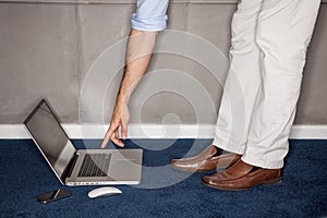 Man standing trying to reach laptop in office