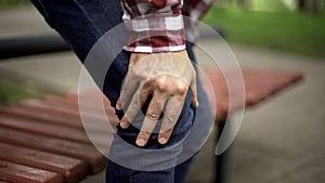 Man standing up from bench feeling sharp knee pain, osteoarthritis, injury