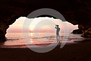 Man standing using camera To take a picture in front of the cave in the morning