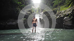 Man standing in the waterfalls and fall on his back in the cold spring.