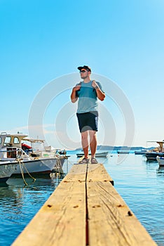 man standing on wooden pier at boats dock at sea bay