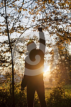 Man standing in the woods facing a setting sun