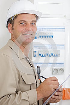 man standing and writing on clipboard