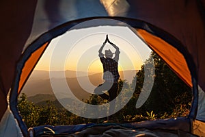 A man standing yoga posture in front of the camp