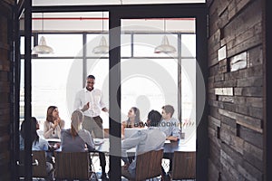 Man stands addressing colleagues at a meeting in a boardroom