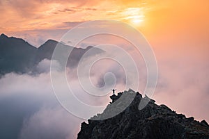 Man stands alone on the peak of rock. Hiker watching to autumn Sun at horizon . Beautiful moment the miracle of nature. Colorful